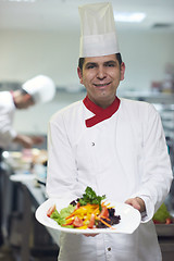 Image showing chef in hotel kitchen preparing and decorating food