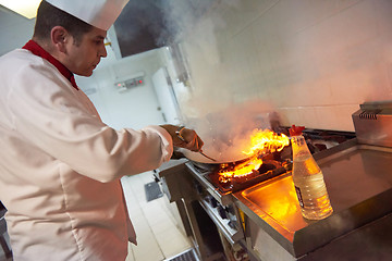 Image showing chef in hotel kitchen prepare food with fire