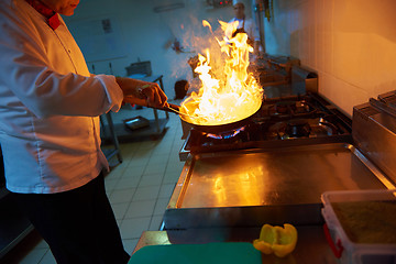 Image showing chef in hotel kitchen prepare food with fire