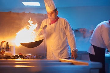 Image showing chef in hotel kitchen prepare food with fire