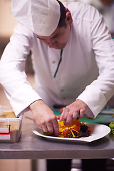 Image showing chef in hotel kitchen preparing and decorating food