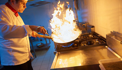 Image showing chef in hotel kitchen prepare food with fire