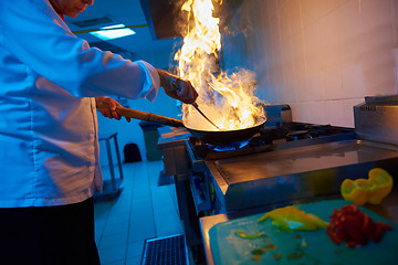 Image showing chef in hotel kitchen prepare food with fire