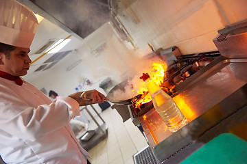 Image showing chef in hotel kitchen prepare food with fire