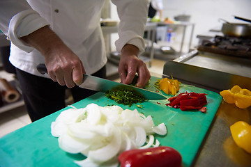 Image showing chef in hotel kitchen  slice  vegetables with knife