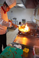 Image showing chef in hotel kitchen prepare food with fire