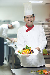 Image showing chef in hotel kitchen preparing and decorating food