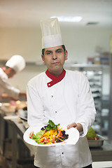 Image showing chef in hotel kitchen preparing and decorating food