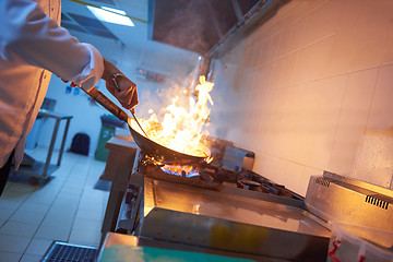 Image showing chef in hotel kitchen prepare food with fire