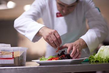 Image showing chef in hotel kitchen preparing and decorating food