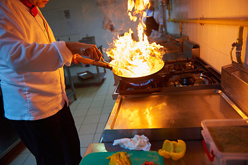 Image showing chef in hotel kitchen prepare food with fire