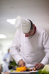 Image showing chef in hotel kitchen preparing and decorating food