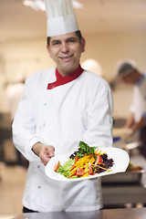 Image showing chef in hotel kitchen preparing and decorating food