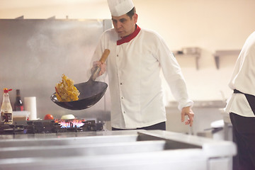 Image showing chef in hotel kitchen prepare food with fire