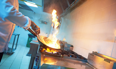 Image showing chef in hotel kitchen prepare food with fire