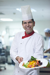 Image showing chef in hotel kitchen preparing and decorating food