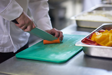 Image showing chef in hotel kitchen  slice  vegetables with knife