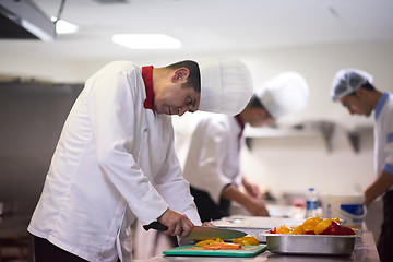 Image showing chef in hotel kitchen  slice  vegetables with knife