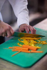 Image showing chef in hotel kitchen  slice  vegetables with knife