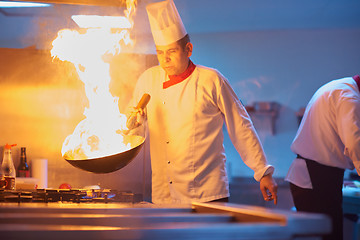 Image showing chef in hotel kitchen prepare food with fire