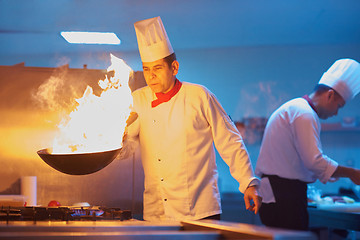 Image showing chef in hotel kitchen prepare food with fire