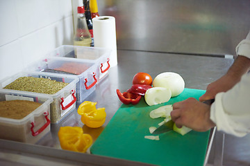 Image showing chef in hotel kitchen  slice  vegetables with knife