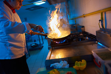 Image showing chef in hotel kitchen prepare food with fire