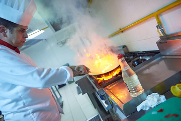 Image showing chef in hotel kitchen prepare food with fire