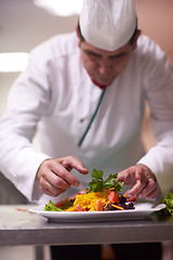 Image showing chef in hotel kitchen preparing and decorating food