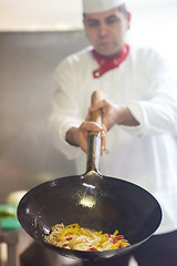 Image showing chef in hotel kitchen prepare food with fire