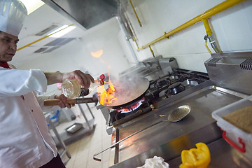 Image showing chef in hotel kitchen prepare food with fire