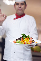 Image showing chef in hotel kitchen preparing and decorating food