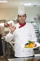 Image showing chef in hotel kitchen preparing and decorating food