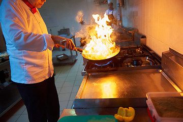 Image showing chef in hotel kitchen prepare food with fire