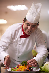 Image showing chef in hotel kitchen preparing and decorating food