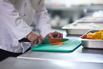 Image showing chef in hotel kitchen  slice  vegetables with knife
