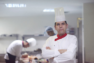 Image showing chef in hotel kitchen preparing and decorating food