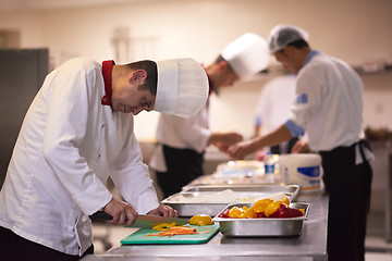 Image showing chef in hotel kitchen  slice  vegetables with knife