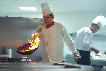 Image showing chef in hotel kitchen prepare food with fire