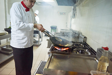 Image showing chef in hotel kitchen prepare food with fire