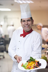 Image showing chef in hotel kitchen preparing and decorating food