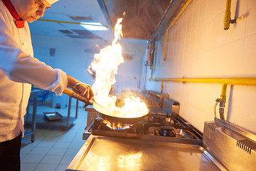 Image showing chef in hotel kitchen prepare food with fire