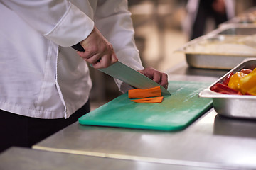 Image showing chef in hotel kitchen  slice  vegetables with knife