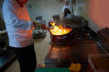 Image showing chef in hotel kitchen prepare food with fire