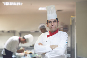 Image showing chef in hotel kitchen preparing and decorating food