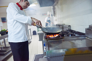 Image showing chef in hotel kitchen prepare food with fire