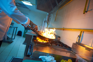 Image showing chef in hotel kitchen prepare food with fire