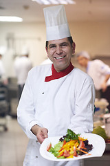 Image showing chef in hotel kitchen preparing and decorating food