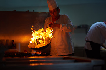 Image showing chef in hotel kitchen prepare food with fire