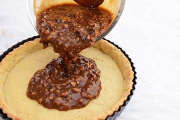 Image showing Pouring pecan pie filling into a pastry case